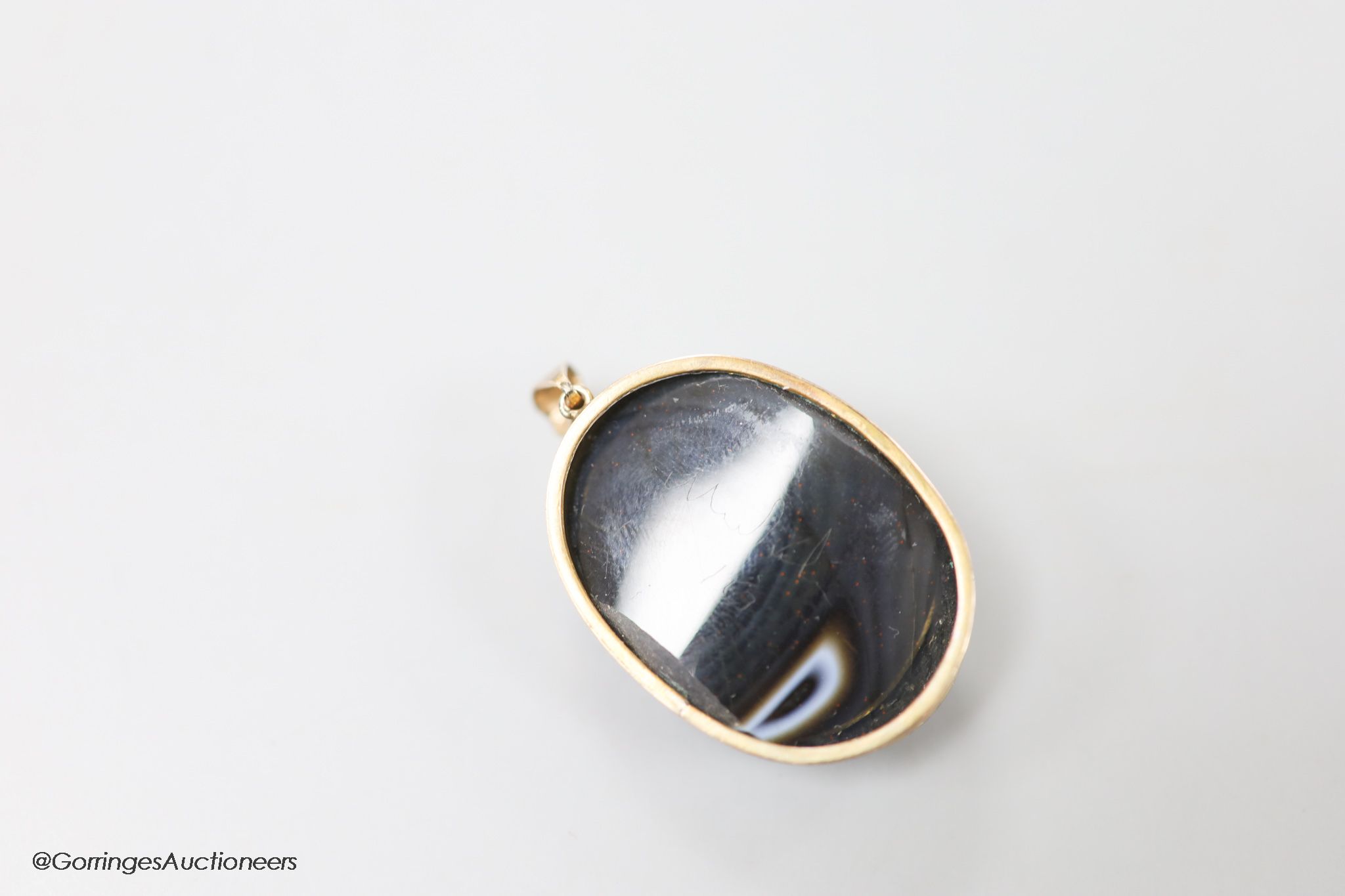 A late Victorian gilt metal mounted oval banded agate pendant, carved with the bust of a lady to dexter, agate length 35mm.